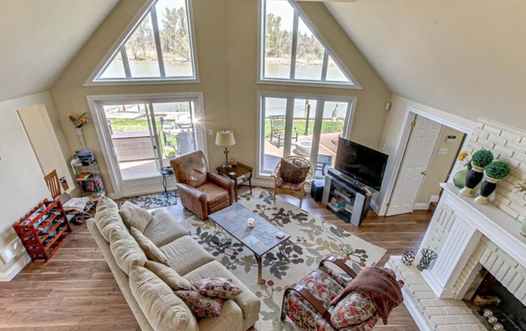 Cozy living room with vaulted ceilings and large windows overlooking a scenic waterfront view.