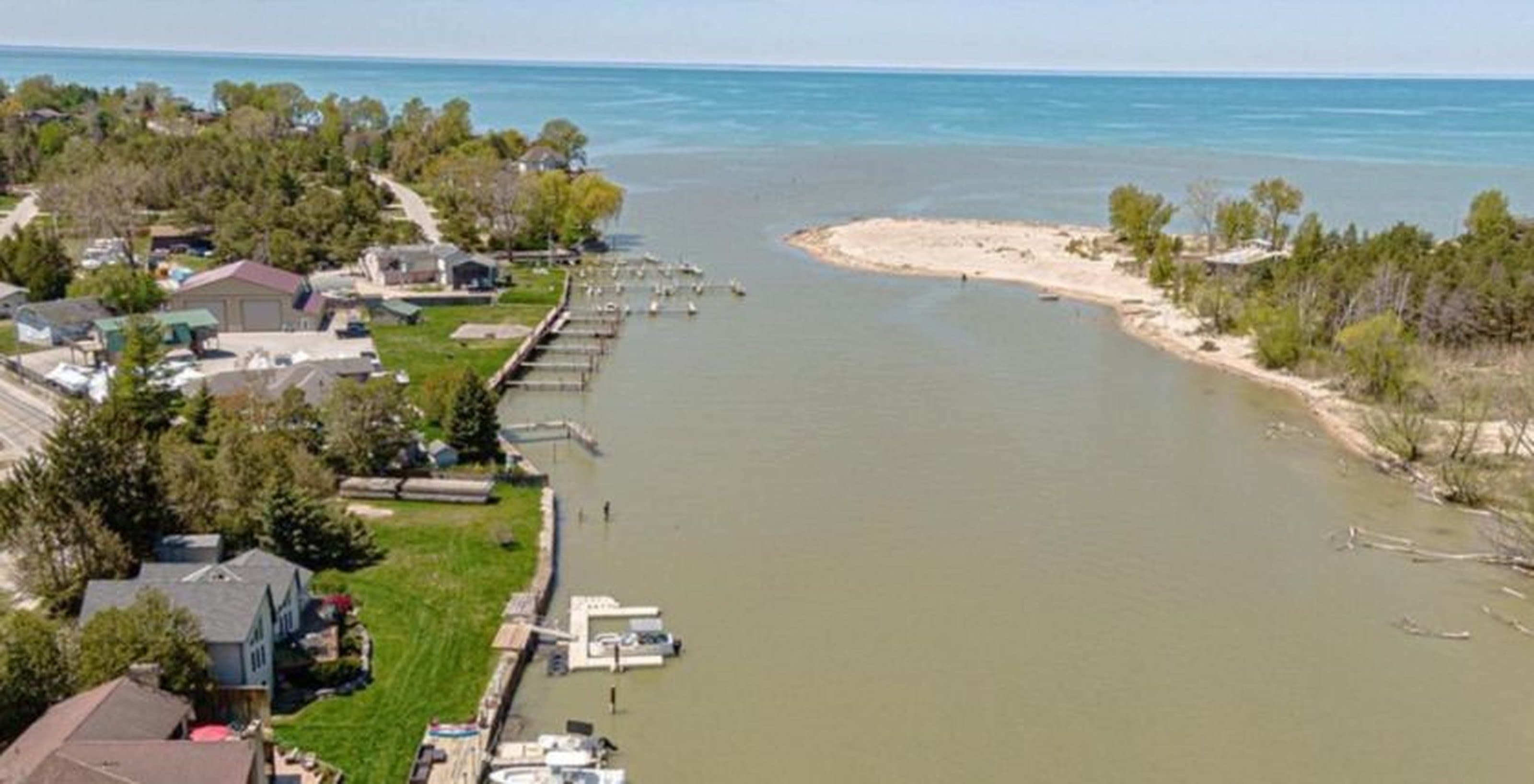 Aerial view of a river inlet with residential docks meeting a large blue lake.